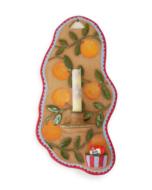 Decorative wall hanging with oranges and a candle on a white background