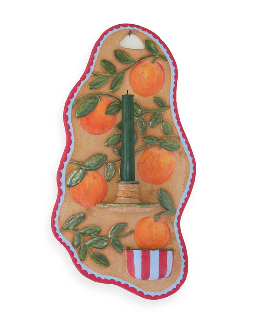 Decorative candle holder with oranges and a candle on a white background