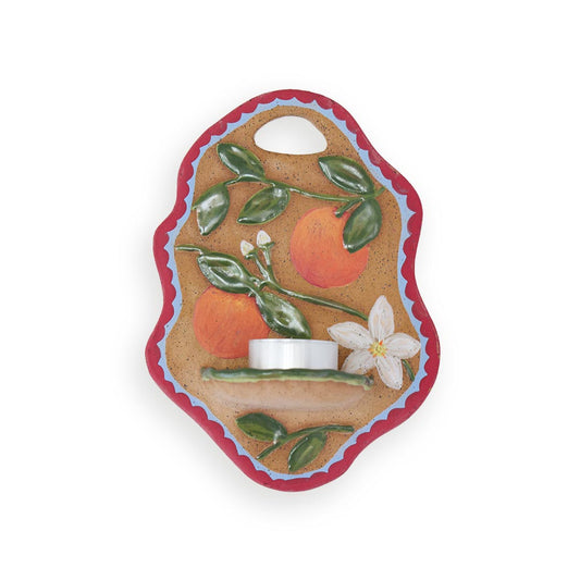 Decorative candle wall hanging with oranges and leaves on a white background.