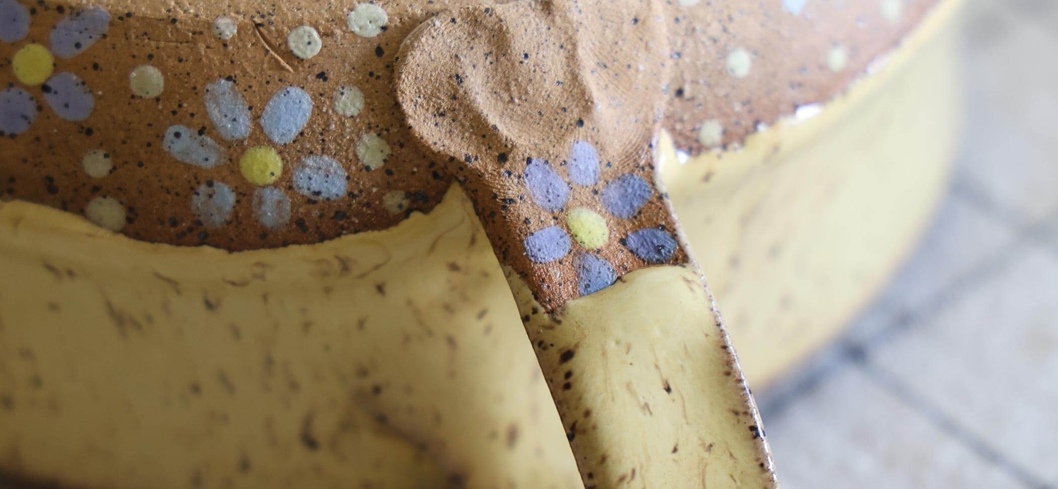 Close-up of a bowl with a flower design on a brown handle. 