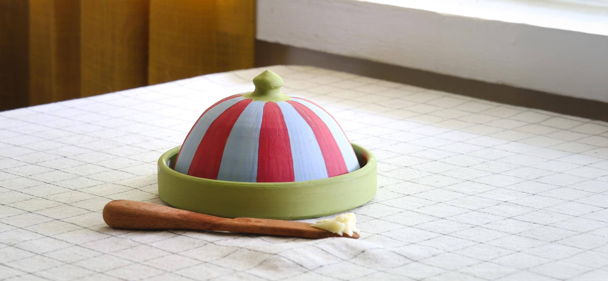 Colorful striped container with a green lid on a textured surface