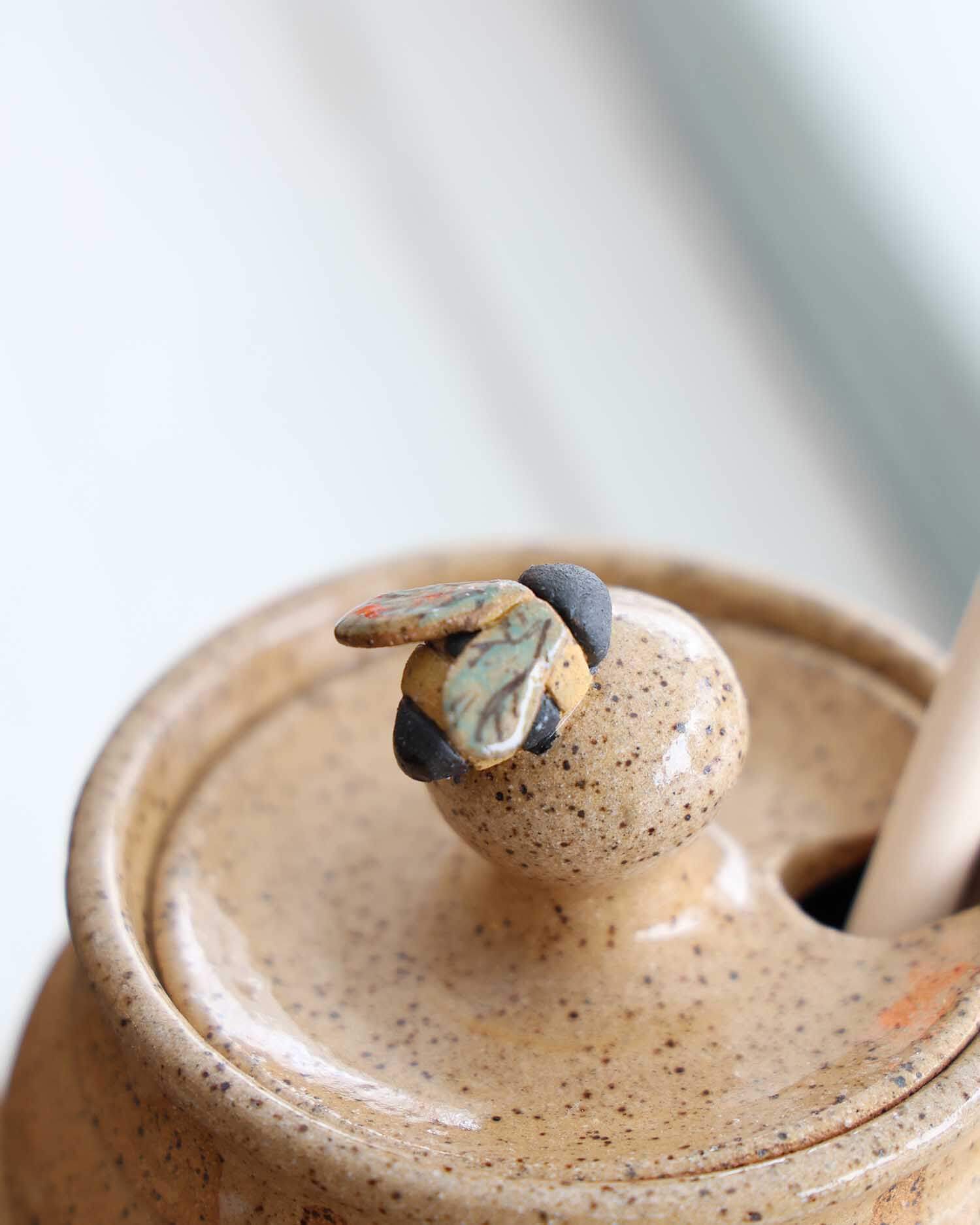 Close-up of a ceramic jar with a lid featuring a decorative handle.